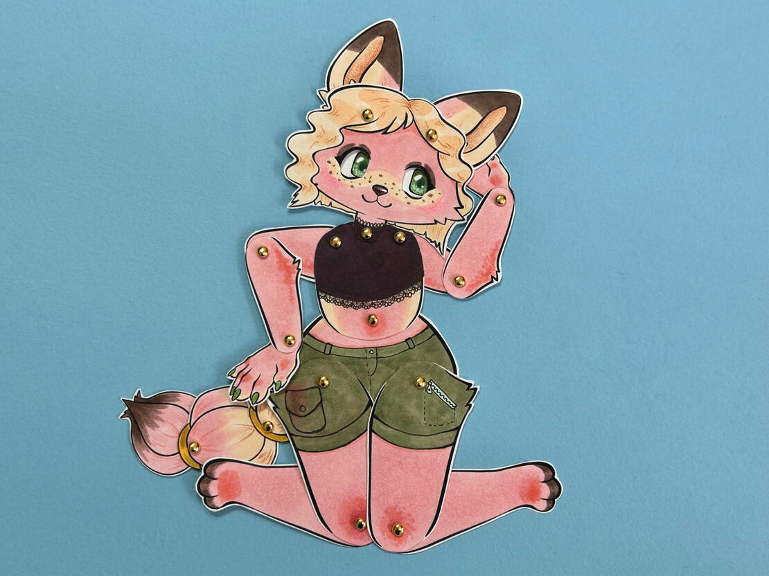 Another photo of an example paper doll, showing my pink fox in a sitting pose, to help show the range of motion in the joints.